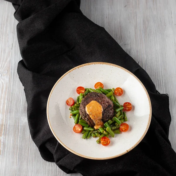 Filé de mignon raro médio assado com feijão verde e tomate cereja fresco, decorado com molho cremoso para um jantar saudável em um restaurante — Fotografia de Stock