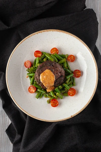 Filé de mignon raro médio assado com feijão verde e tomate cereja fresco, decorado com molho cremoso para um jantar saudável em um restaurante — Fotografia de Stock