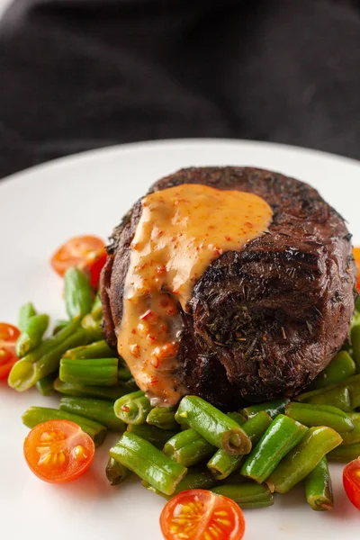 Close up view of a medium rare mignon steak, roasted with green beans and fresh cherry tomatoes, decorated with creamy sauce — Stock Photo, Image