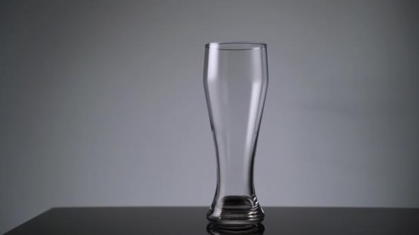 Eine Flasche Bier neben ein leeres Bierglas stellen — Stockvideo