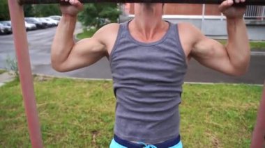 Yakın adam açık havada yatay bar üzerinde pull-up yapıyor 