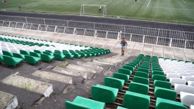 Adam yavaş çekimde koltuklar arasında stadyum merdivenleri kadar çalışan