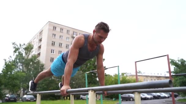 Joven está haciendo flexiones de lanzadera en barras paralelas al aire libre — Vídeo de stock