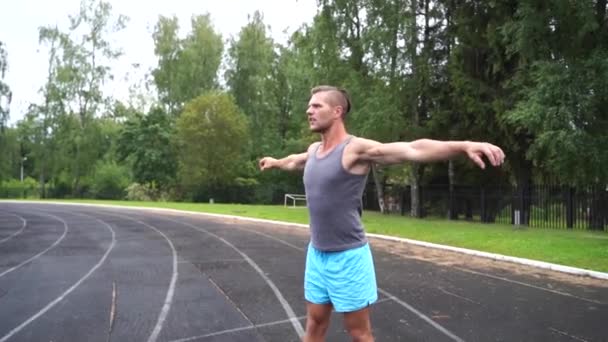 Attractive young sportsman warming up shoulders before street workout — Stock Video