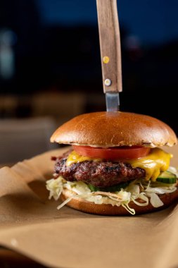 Eritilmiş peynir ve yağlı sığır köftesi ile sulu cheeseburger bir zanaat kağıt üzerinde servis