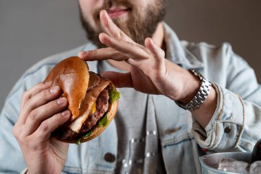 Genç sakallı adam buz gibi bira ile gevrek pastırma ile sulu bir hamburger yiyor