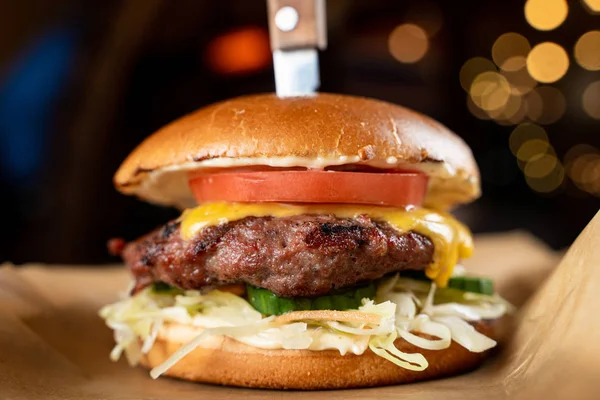 Close up of juicy cheeseburger with melted cheese and fat beef patty with knife in it