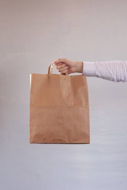 Genç kadın kahverengi bir teslimat zanaat kağıt torba taşıyor