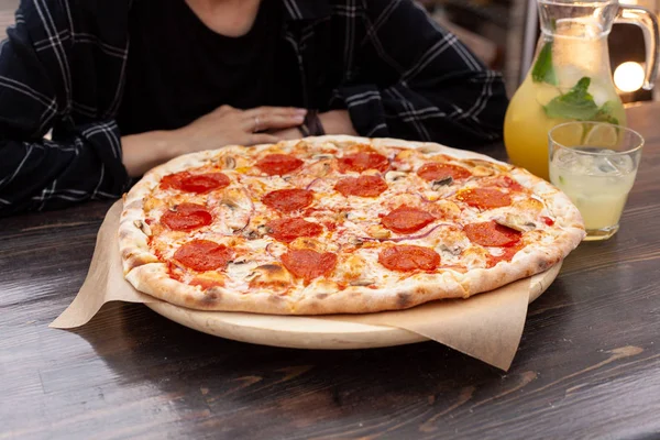Genç Avrupalı kadın eritilmiş peynir ve narenciye limonata ile İtalyan pepperoni pizza yiyor