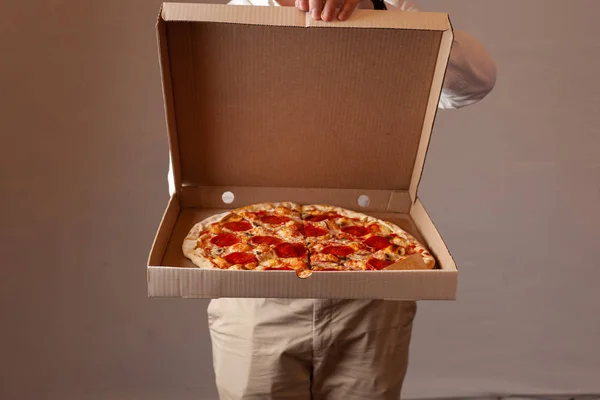 Genç adam champignon mantar ile acı pepperoni pizza ile bir teslimat karton kutu açıyor