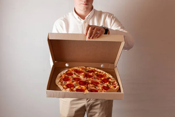 Genç adam champignon mantar ile acı pepperoni pizza ile bir teslimat karton kutu açıyor