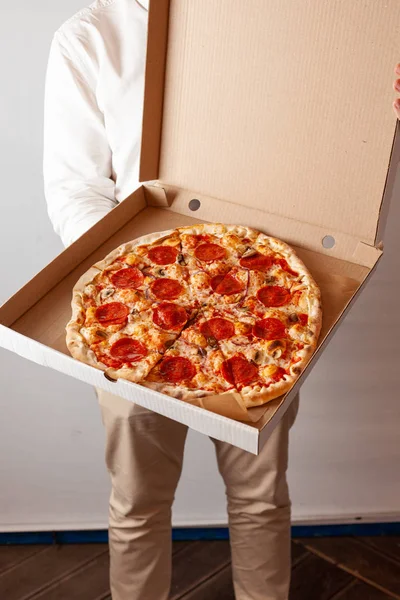 Genç adam champignon mantar ile acı pepperoni pizza ile bir teslimat karton kutu açıyor