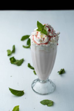 Klasik vanilyalı milkshake. Krem şantili. Etrafı nane yapraklarıyla bembeyaz.