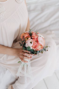 Gelin elinde düğün çiçeği pembe buketi, beyaz kumaş arka plan