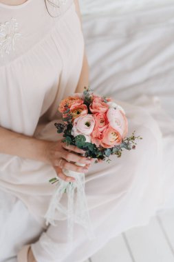 Gelin elinde düğün çiçeği pembe buketi, beyaz kumaş arka plan