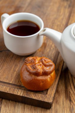 Rus piroshkisi ahşap masanın üzerinde, fincanda siyah çay, yakın plan.