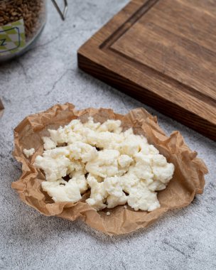 Taş masada kraft kağıdına sarılı çiftlik tahıllı ricotta peyniri.