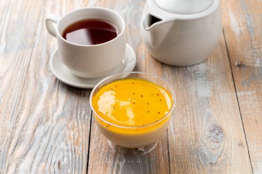 Mango panna cotta kremalı ve mango püresi ahşap masada plastik bardakta.