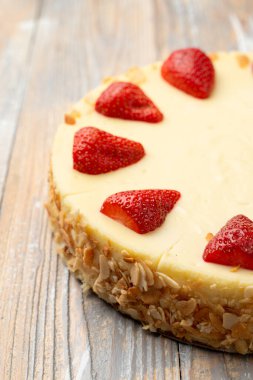 Klasik çilekli cheesecake ve sınırda badem gevreği, yakın çekim, nefis reklam fotoğrafı.
