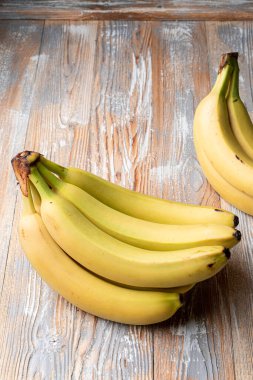 Hafif ahşap masada mutlu sarı muzlar, katalog fotoğrafı.