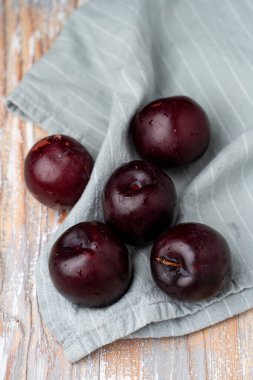 Keten kumaşta mor erikler, yakın çekim, seçici odaklanma.