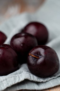 Keten kumaşta mor erikler, yakın çekim, seçici odaklanma.