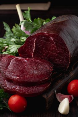 Stüdyo fotoğrafı, ham fileto, dilimlenmiş ve otlarla çevrili, koyu arkaplan 