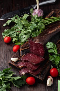 Tütsülenmiş ve kurutulmuş mignon, sulu ve lezzetli, esrarlı arka planda otlar ve baharatlarla, reklam fotoğrafı