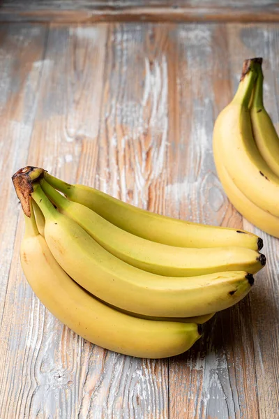 Hafif ahşap masada mutlu sarı muzlar, katalog fotoğrafı.