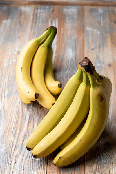 Hafif ahşap masada mutlu sarı muzlar, katalog fotoğrafı.