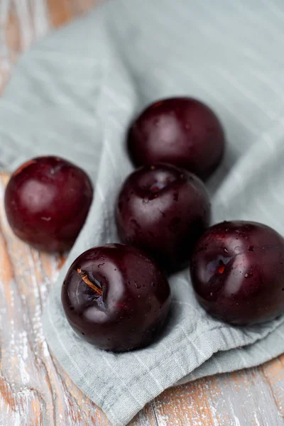 Keten kumaşta mor erikler, yakın çekim, seçici odaklanma.