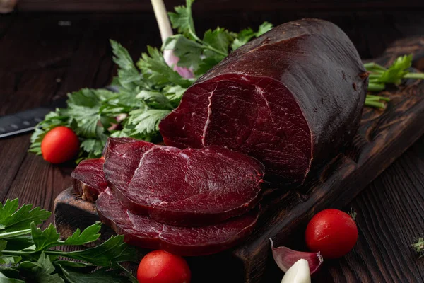 Çiğ fileto, dilimlenmiş ve otlarla çevrili, koyu arka planda, bir pazar kataloğu için fotoğraf