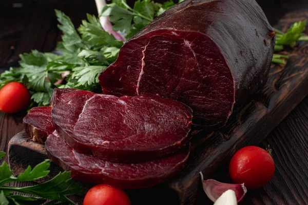 Çiğ fileto, dilimlenmiş ve otlarla çevrili, koyu arka planda, bir pazar kataloğu için fotoğraf