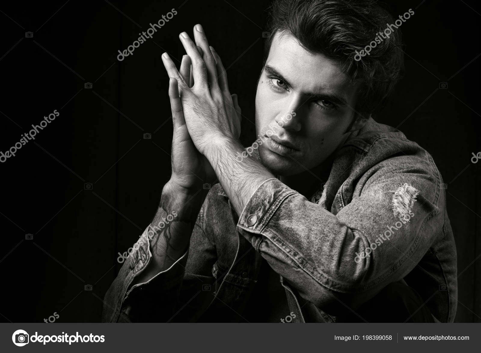 Closeup of black and white masculine portrait on a black background young handsome man posing and looking at camera fashion photograph professional model