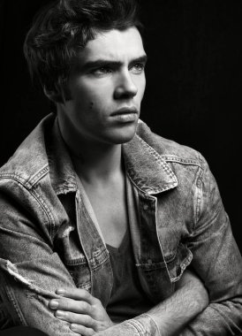 Genç yakışıklı adam siyah arka plan üzerine siyah beyaz portre. Ciddi bir bakın