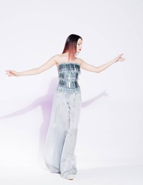 Genç güzel kadın dans. Gümüş moda bluz ve geniş bacak pantolon. Beyaz bir duvar üzerinde pembe gölge