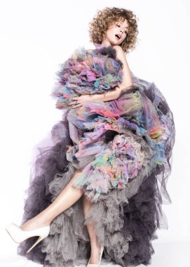 Renkli katmanlı elbiseyle dans neşeli genç kadın. Güzel kıvırcık saçlı. Tarafsız beyaz arka plan