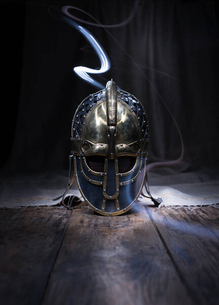 Warrior Spirit. Beautiful, historic helmet of an ancient warrior on a wooden table. Armor on a dark background