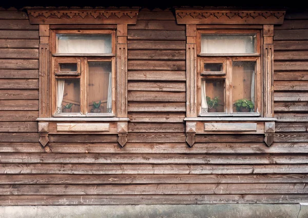 The facade of the old wooden houses with windows. Rustic architecture of Russia