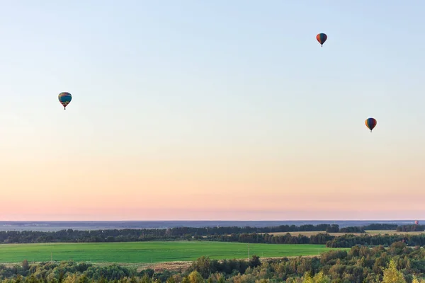 Flying in a balloon. Three objects in the air against a cloudless sky. Evening landscap