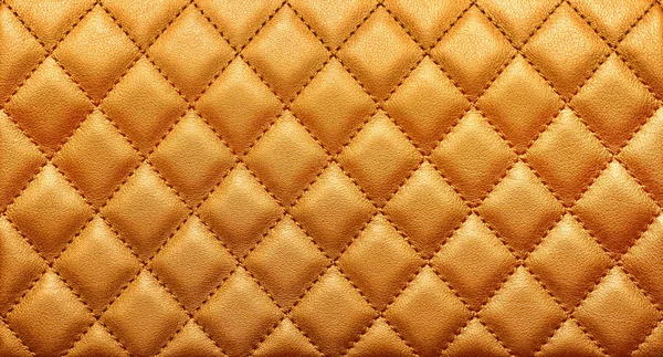 Close-up texture of genuine leather with rhombic stitching. Rich gold color — Stock Photo, Image