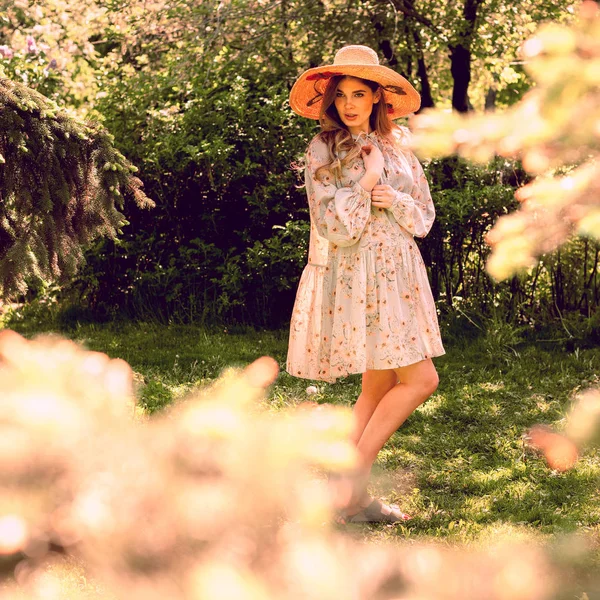 Красивая молодая женщина позирует в парке. Летнее платье и шляпа . — стоковое фото