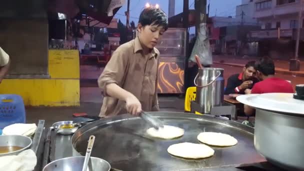 Маленький мальчик-патан делает паратху на большой сковороде — стоковое видео