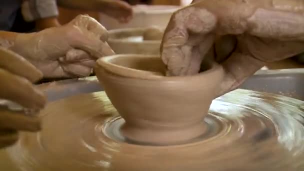 Vue rapprochée des mains masculines et féminines travaillant ensemble avec de l'argile sur une roue de poterie. — Video