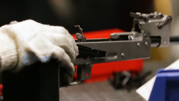 Производство оружия. Работница в перчатках собирает автоматическую винтовку. Закрыть вид — стоковое видео