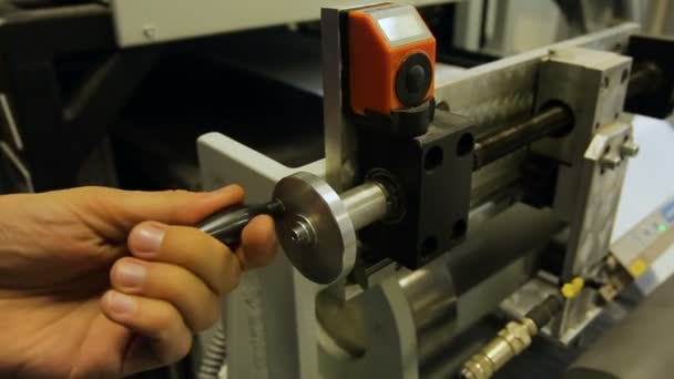 El trabajador en manual gira la manija del aparato grueso para el ajuste de la distancia. — Vídeo de stock