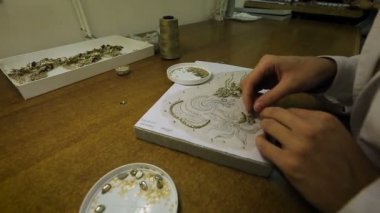 Bir kadın pullarla eline bir desen işliyor. Dikiş endüstrisinde, bir kadın pul işliyor..