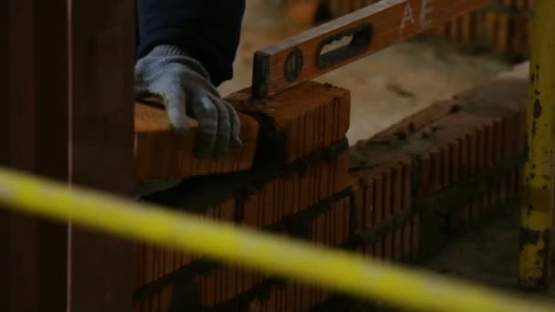 En man i arbetshandskar gör murverk med en spatel på byggarbetsplatsen. — Stockvideo