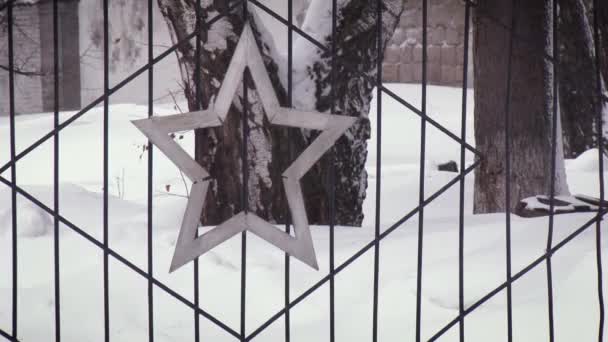 Χιονίζει και παρασύρεται στο φόντο ενός σιδερένιου φράχτη σε σχήμα αστεριού. Κλείσιμο εξωτερικής προβολής. — Αρχείο Βίντεο
