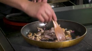 Erkek ellerinin kızartma şampiyonunu, soğanı ve kıymayı yağlı tavada karıştırmasını yakından izleyin. Akşam yemeği hazırlığı.